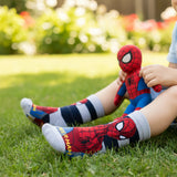 An image of a child wearing Supersox Marvel Spider-Man Printed Crew Socks while sitting on grass and holding a Spider-Man plush toy