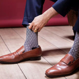 An image of grey textured formal socks worn with brown leather loafers and black trousers in a styled product shot.